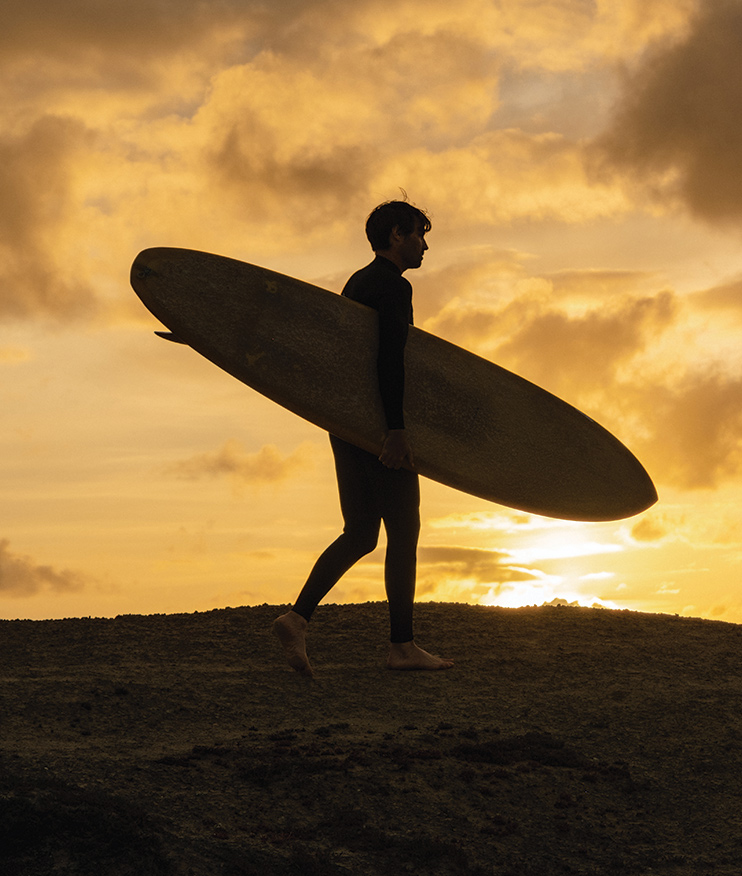 http://Sunset%20with%20man%20holding%20surfboard